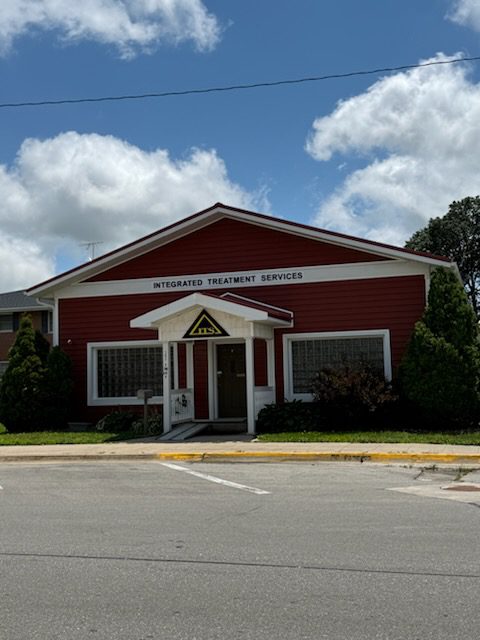 Red and white building marked "Integrated Treatment Services." Features a welcoming entrance and landscaped greenery, indicating a supportive environment.